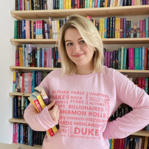 Girl with pink jumper on holding a pile of books