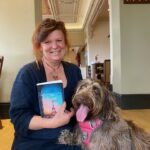 Author Juliet Greenwood pictured holding her book last train from paris and with her shaggy dog