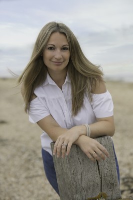 A photo of Lorna Cook on the beach, leaning against a breakwater.