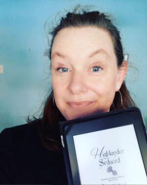 Author Jayne Castel with dark hair pulled back and black top, holding kindle